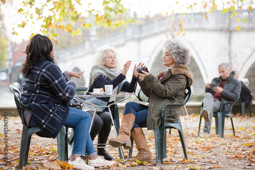 Portrait smiling, happy active senior women friends drinking coffee at autumn park cafe