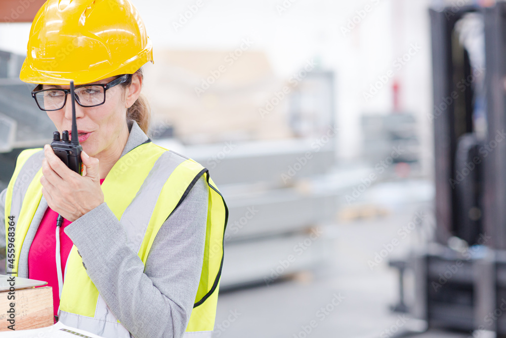Female worker using laptop and walkie-talkie in factory Female worker using laptop and walkie-talkie in factory