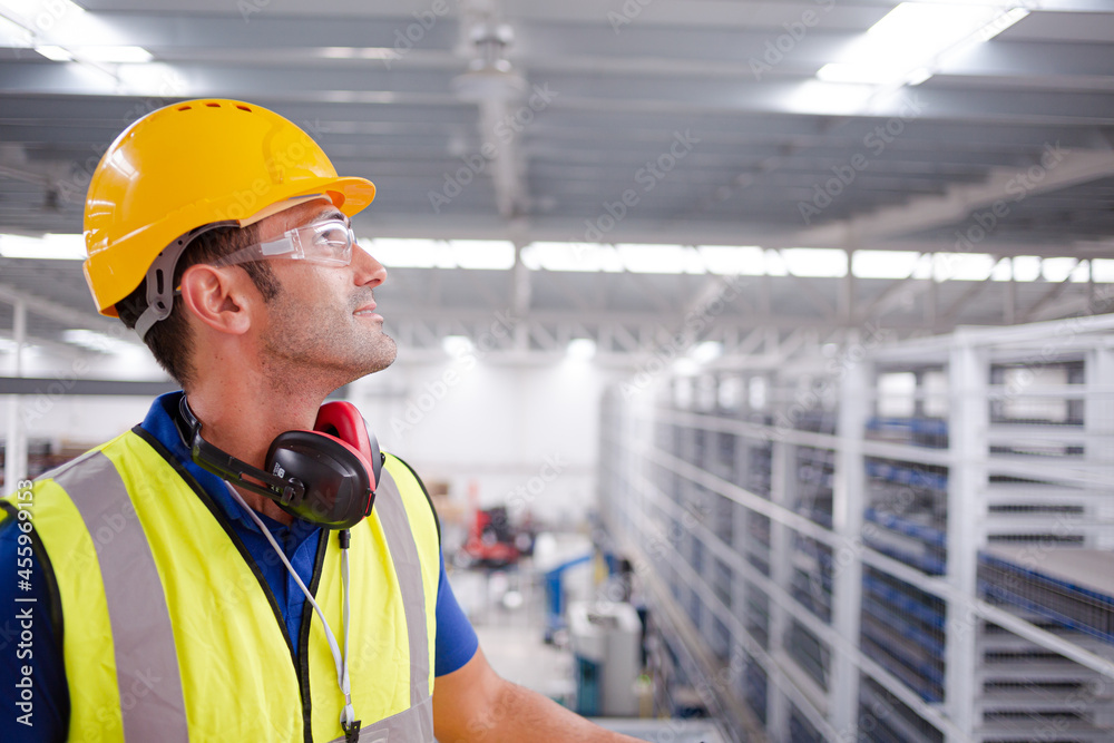 Portrait serious male worker in protective eyewear and hard-hat in factory Portrait serious male worker in protective eyewear and hard-hat in factory
