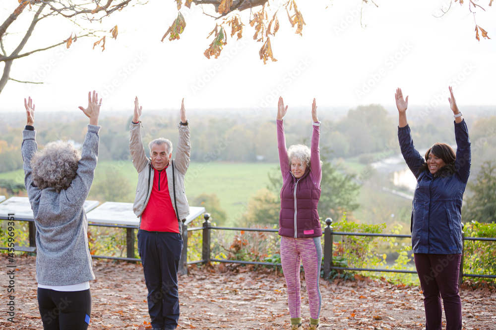 Affectionate active senior man and women doing exercises at autumn park pond