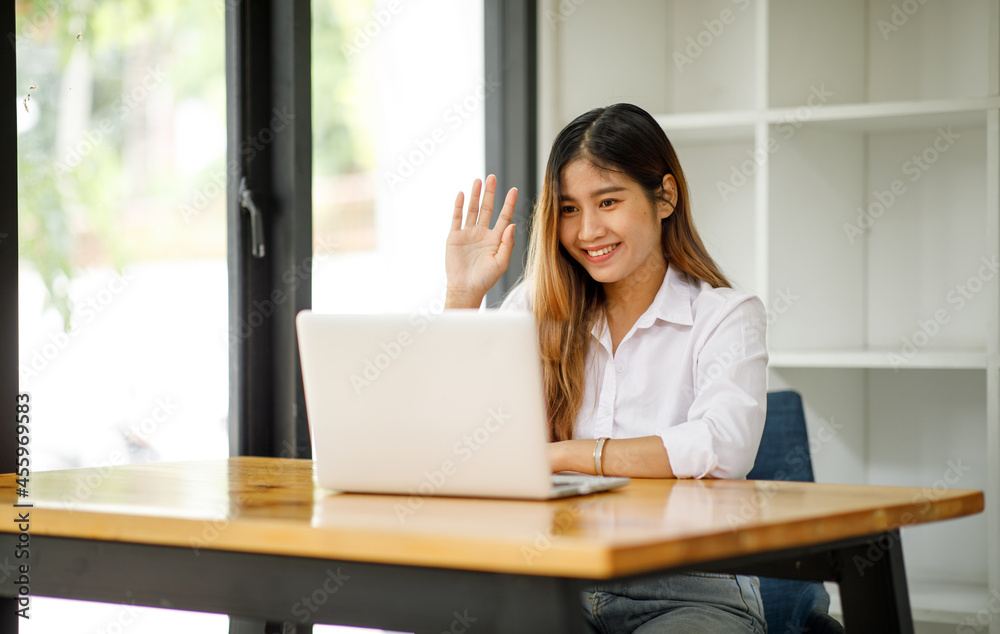 Young asian woman having conference video call using laptop talking to coworker online audience sitting at office desk in evening. Young asian woman having conference video call using laptop talking to coworker online audience sitting at office desk in evening.
