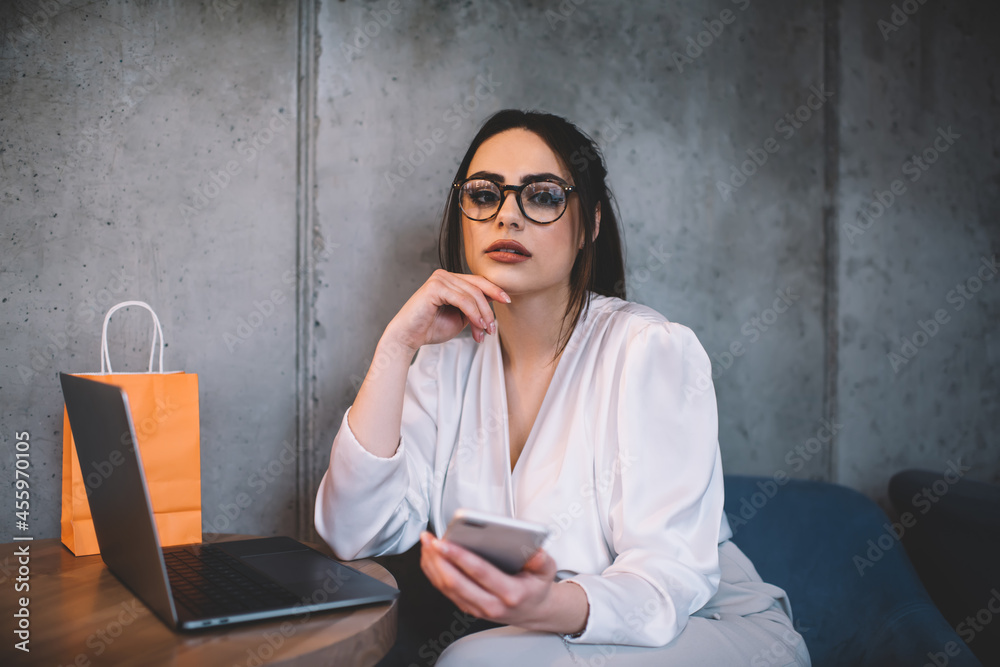Serious woman using laptop and mobile phone while sitting at cafe Serious woman using laptop and mobile phone while sitting at cafe