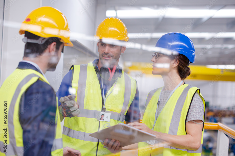 Supervisors and worker with clipboard talking in factory Supervisors and worker with clipboard talking in factory