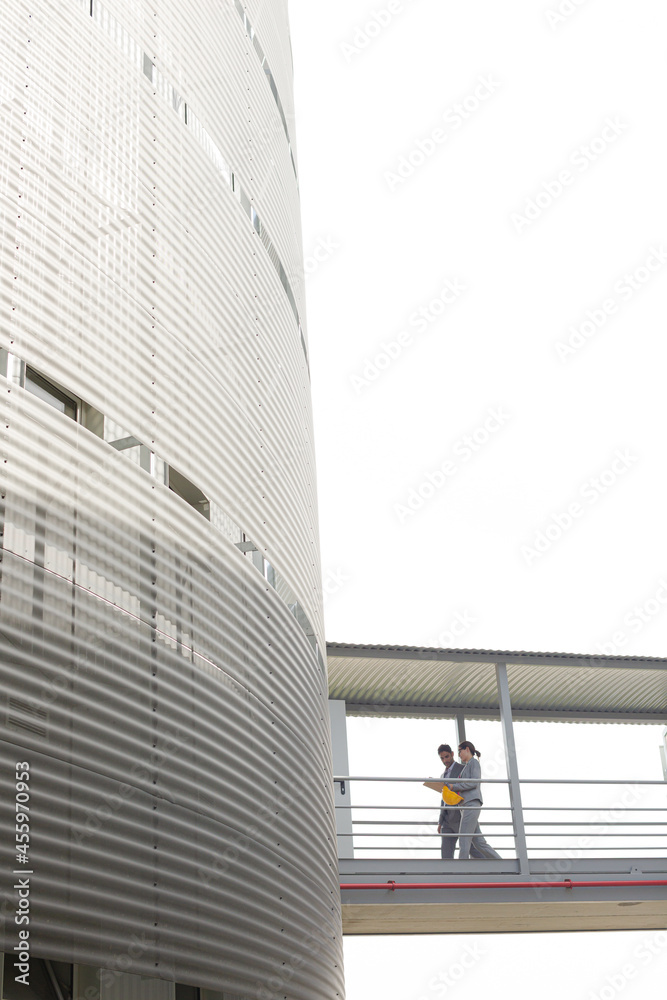 Obraz premium Supervisors walking on elevated walkway between factory buildings