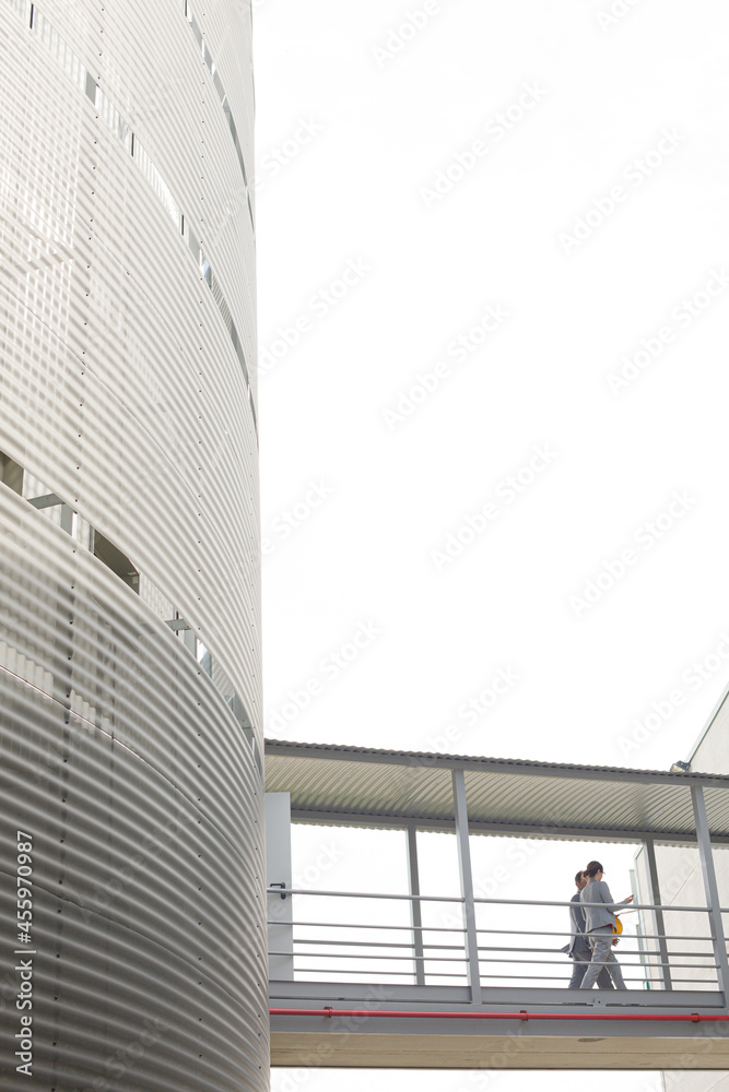 Fototapeta premium Supervisors walking on elevated walkway between factory buildings