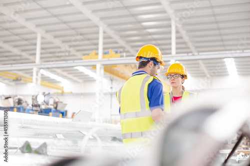 Smiling female worker talking with coworkers in factory