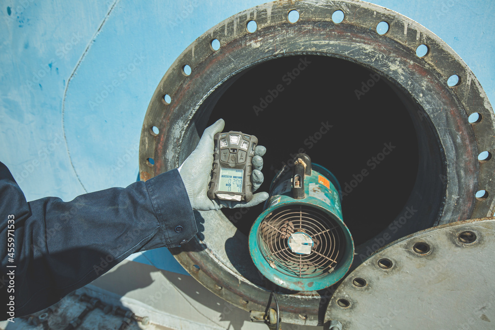 Worker hand holding gas detector inspection safety gas testing at front manhole tank