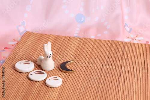 Japanese backgound. chopstick stands with the image of a moon rabbit on the background of a bamboo mat and pink fabric in a traditional style. The concept of the mid-autumn photo