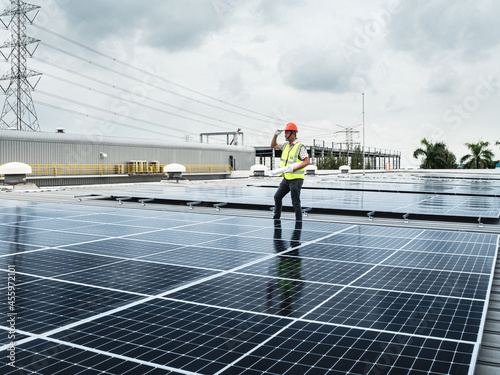  male engineer checks a photovoltaic (solar) plant and uses a recording tablet. mechanic in protective helmet. Man in uniform holding tablet.