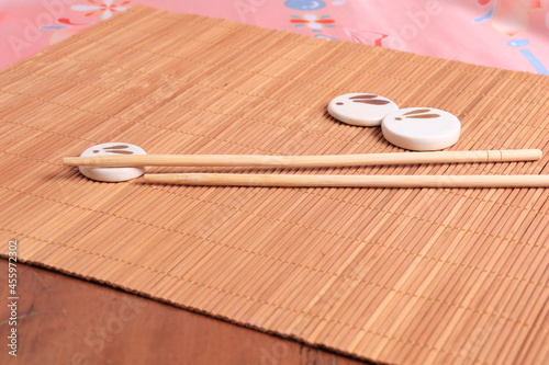 Japanese chopsticks and coasters. With the image of a moon rabbit on the background of a bamboo mat and pink fabric in a traditional style. The concept of the mid-autumn festival photo