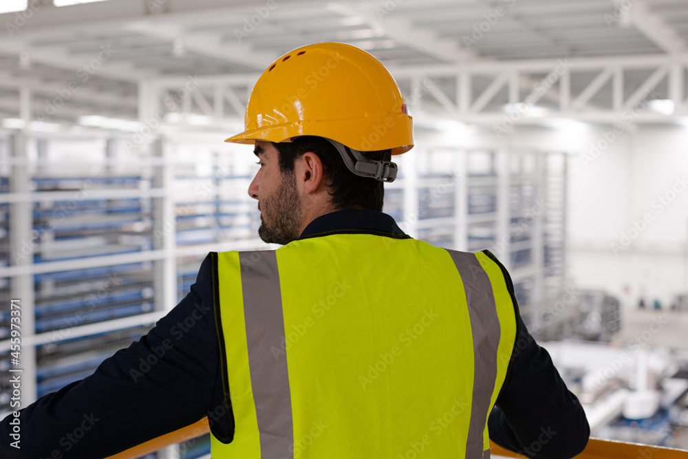 Serious male supervisor leaning on platform railing in factory