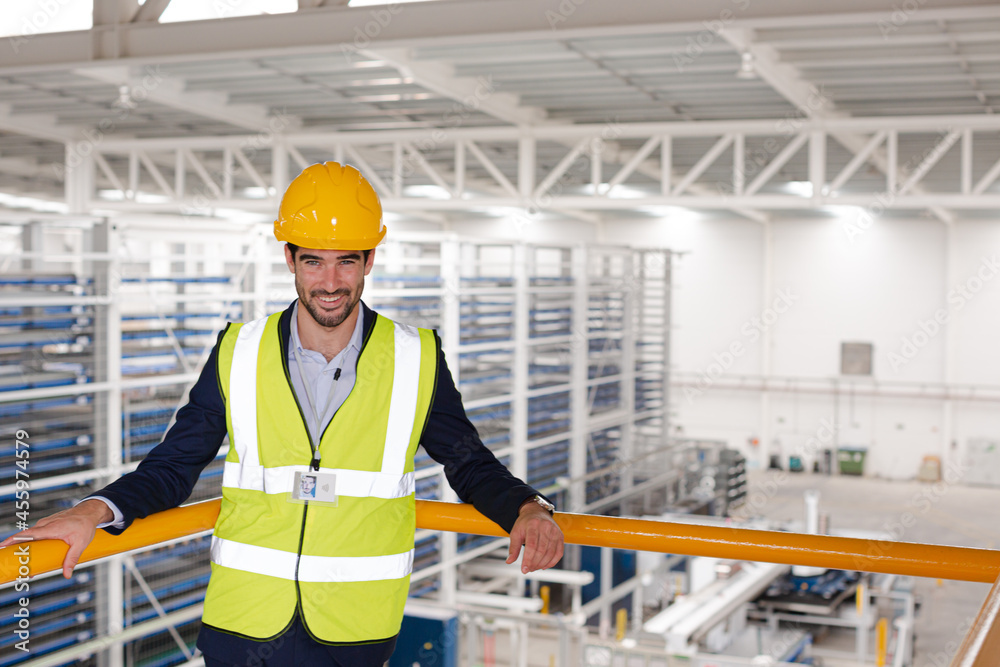 Serious male supervisor leaning on platform railing in factory Serious male supervisor leaning on platform railing in factory