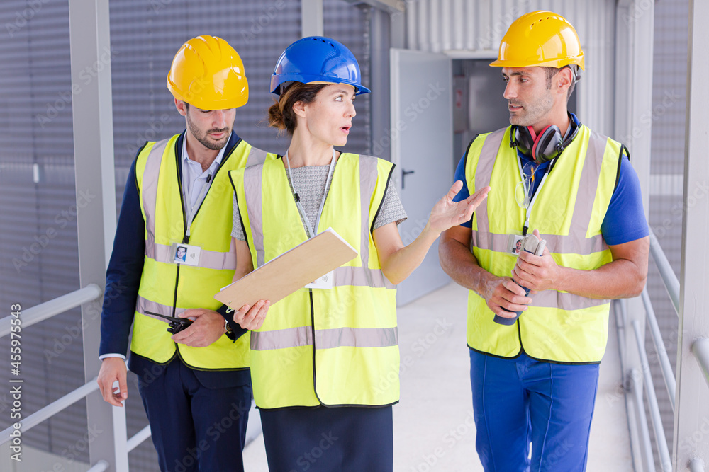 Supervisors and worker with clipboard talking in factory Supervisors and worker with clipboard talking in factory