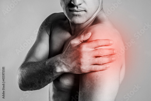 Man suffering from shoulder pain, closeup. Black and white photo