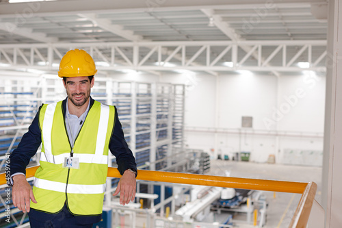 Serious male supervisor leaning on platform railing in factory
