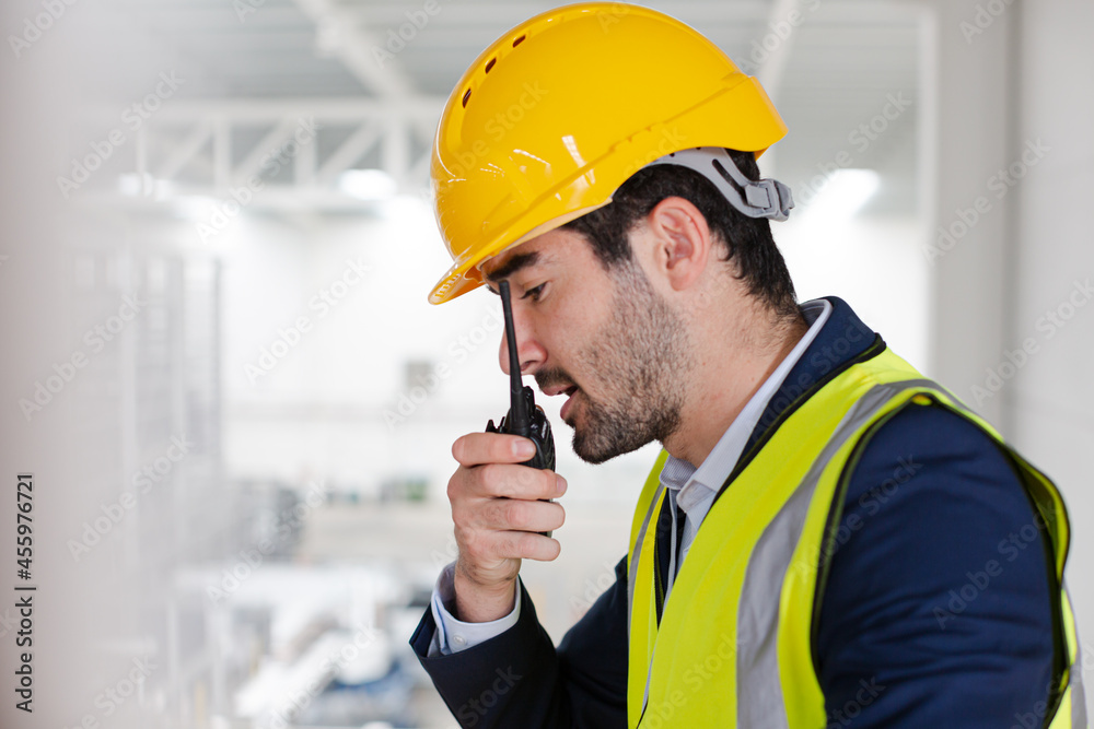 Male supervisor using walkie-talkie on platform in factory