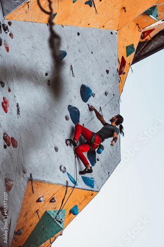 Hard level. Young man professional rock climber practicing at training center in sunny day, outdoors. Concept of healthy lifestyle, tourism, nature, motion.