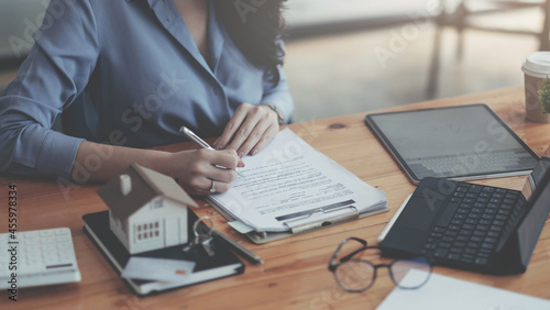 Tableau sur toile Close up real estate agent with house model hand putting signing contract, signing of modest agreements form in office