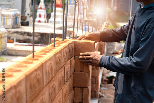 Wallpaper Mural Builder carefully puts red brick on the masonry. Quick work bricklayer. Guy measures level masonry. Man is building brick wall. Correctly calculate material. Builder manually carries brick structure Torontodigital.ca