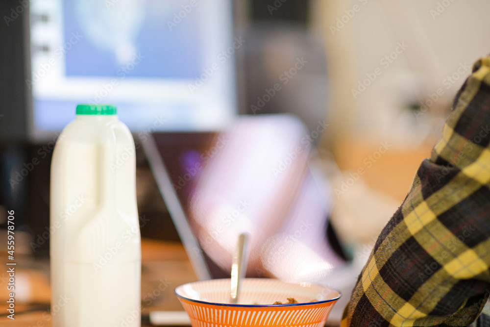 Bowl of cereal and bottle of milk on desk Bowl of cereal and bottle of milk on desk