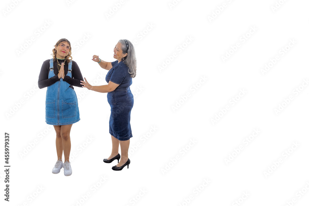 Mature mother scolding her teenage daughter with angelic expression, white studio background, wide smile, light makeup, casual style, denim clothes. Two generations of Latin women. Space for text