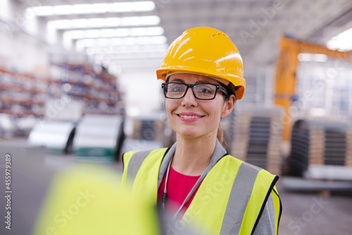 Portrait confident, smiling female worker in steel factory