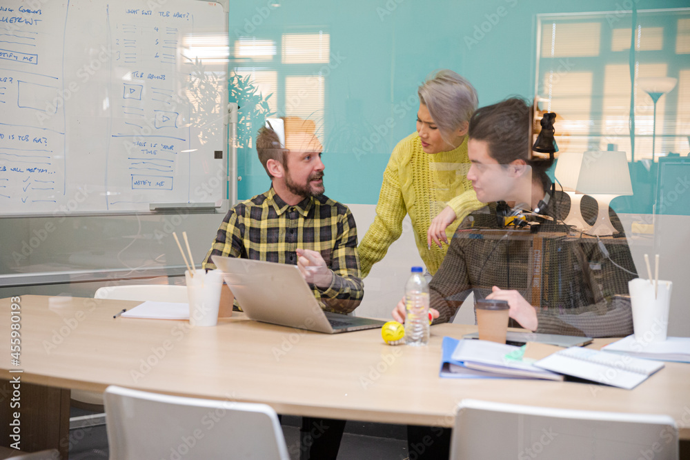 Three colleagues working at computer in conference room