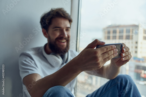 bearded man sitting on the windowsill in headphones in headphones technology
