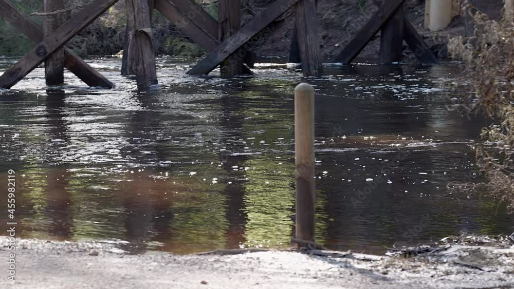 Waters of river in flood flows under old historic wooden Bridge. Floodwater levels seen on pylon. Sound of turbulence Waters of river in flood flows under old historic wooden Bridge. Floodwater levels seen on pylon. Sound of turbulence