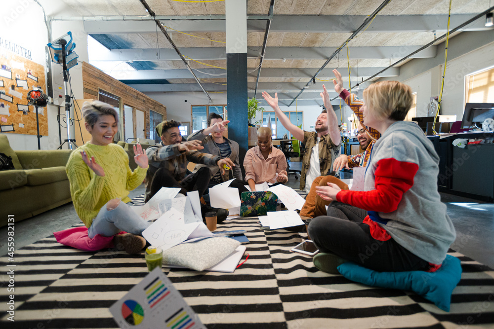 Fototapeta premium Team sitting on office floor, discussing paperwork