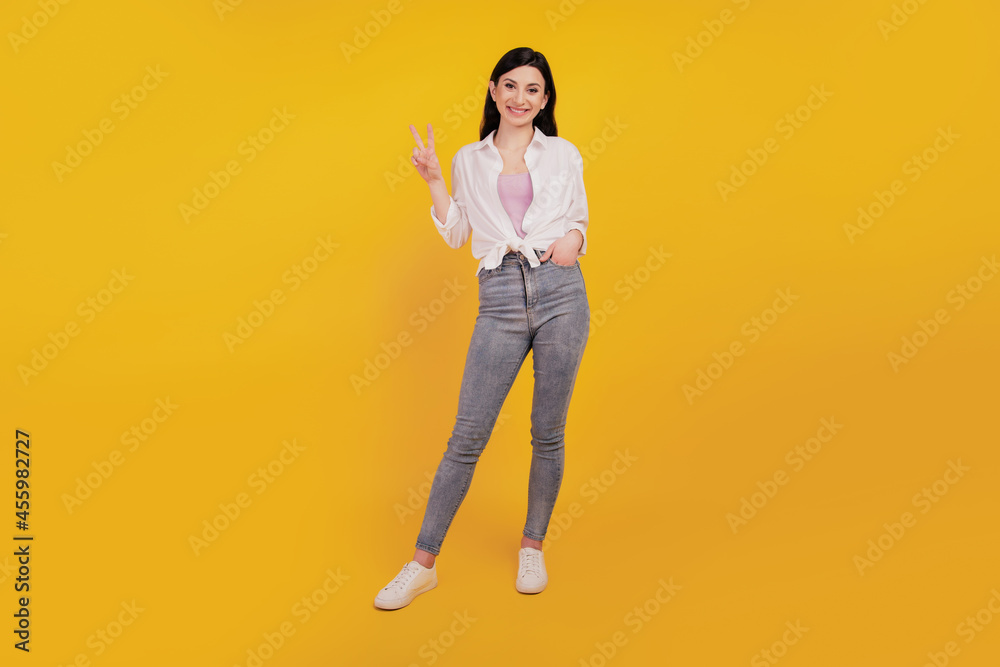 Portrait of gorgeous lovely firendly pretty girl show v-sign on yellow background Portrait of gorgeous lovely firendly pretty girl show v-sign on yellow background