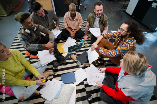 Team sitting on office floor, discussing paperwork