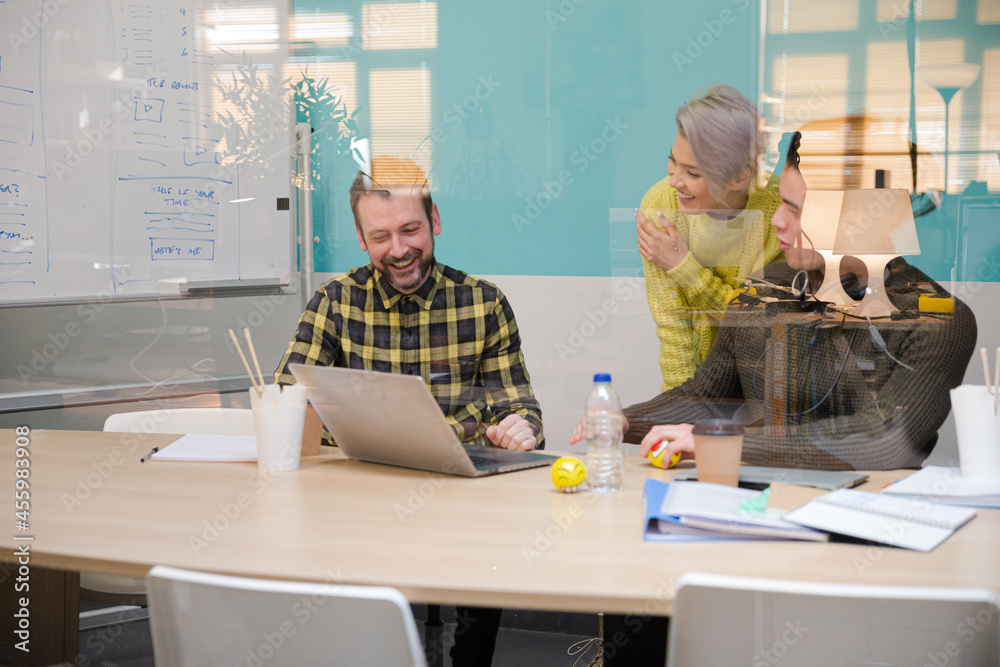 Three colleagues working at computer in conference room
