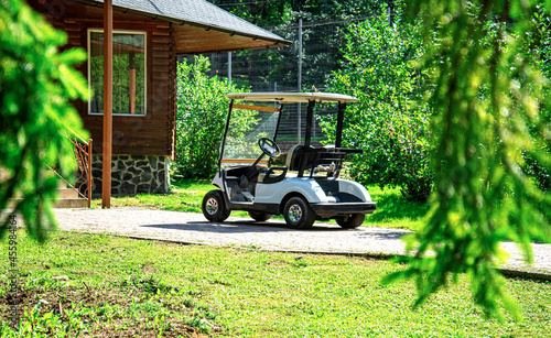 White golf cart in the parking lot near the building.