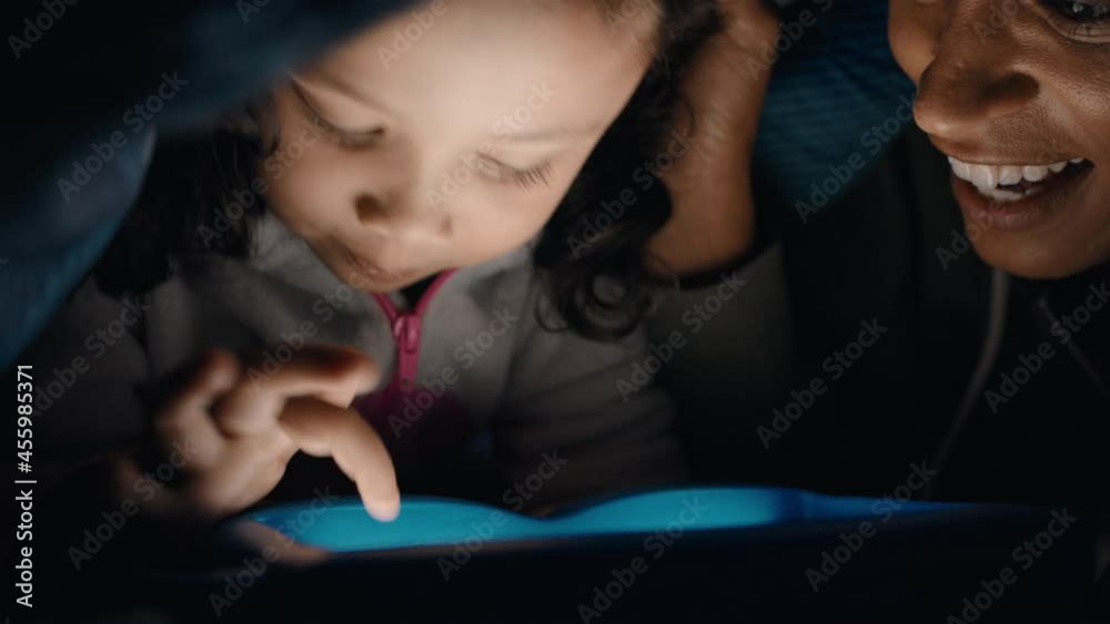 happy mother and daughter using tablet computer under blanket playing games on touchscreen technology relaxing having fun before bedtime 