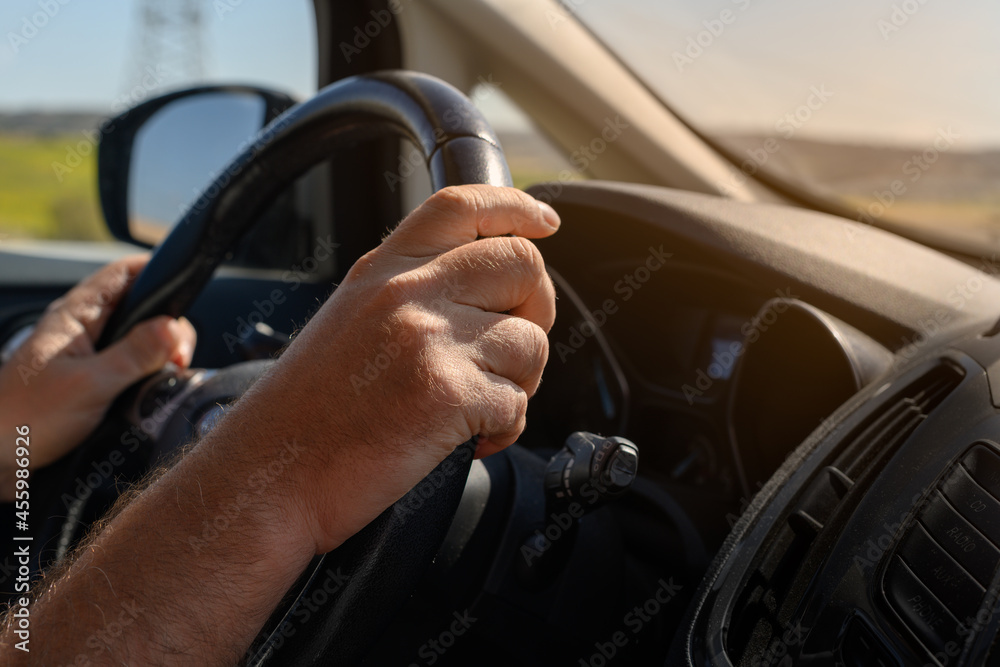 Close-up of a man's hands on a car steering wheel