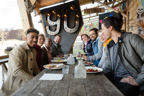 Portrait of smiling friends eating at restaurant outdoor patio