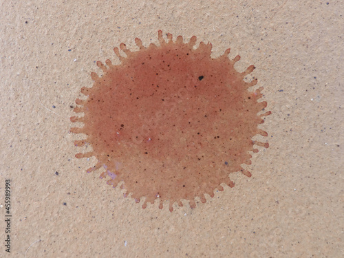 Red wine drop in a bron floor. Drop has the shape as a coronavirus