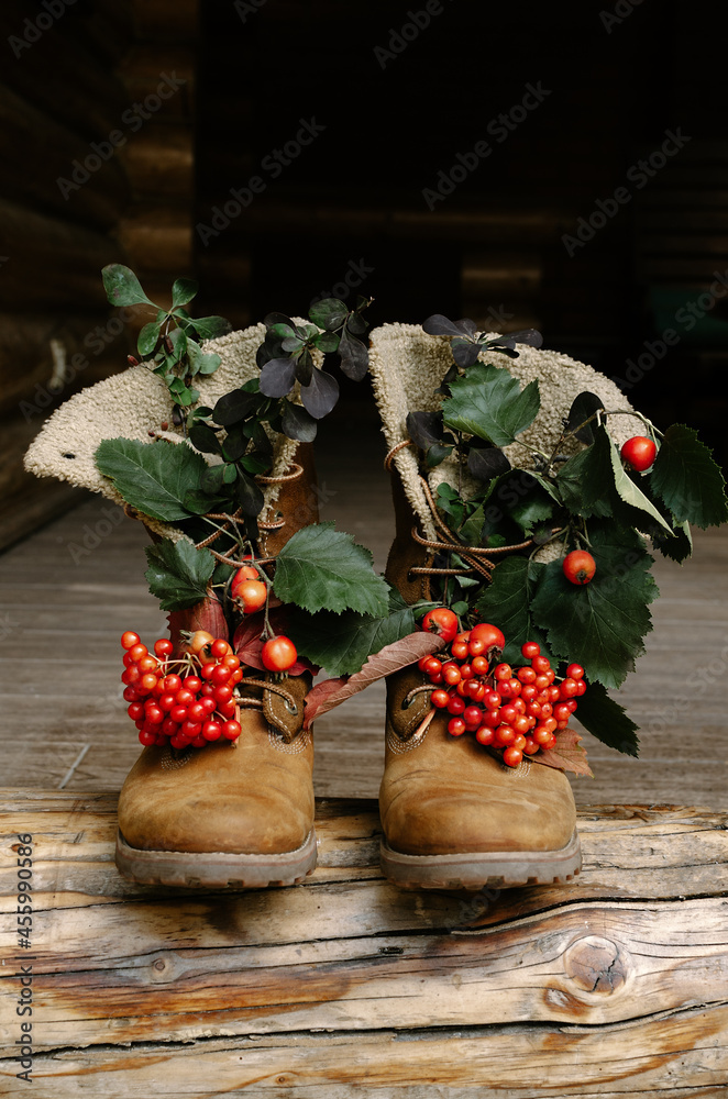 Tracking boots with autumn berries and leaves standing on the porch of a country house. Tracking boots with autumn berries and leaves standing on the porch of a country house.