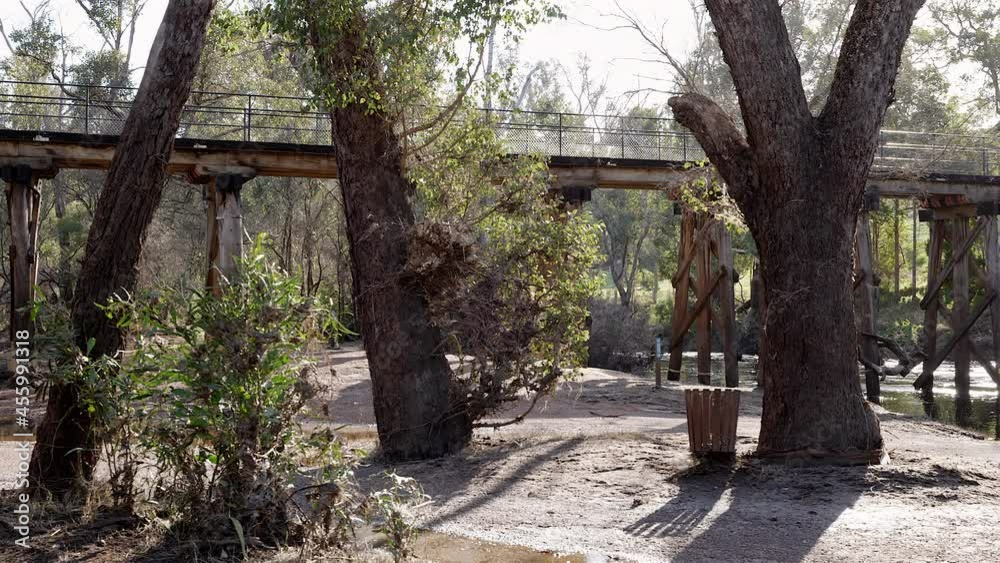 Pan along historic wooden railway bridge which crosses fast flowing Blackwood River. Gum trees on both banks. Bike rider crosses. Native birds chirp Pan along historic wooden railway bridge which crosses fast flowing Blackwood River. Gum trees on both banks. Bike rider crosses. Native birds chirp