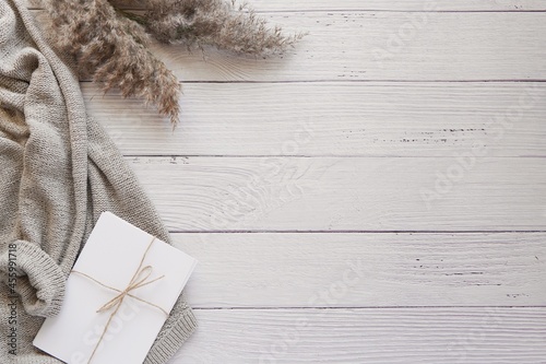 Boho workspace flat lay with cozy sweater, pampas grass, bohemian wooden background with space for text or design.