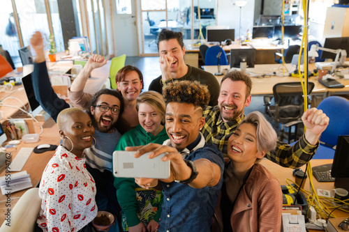 Team talking group selfie with smartphone in office