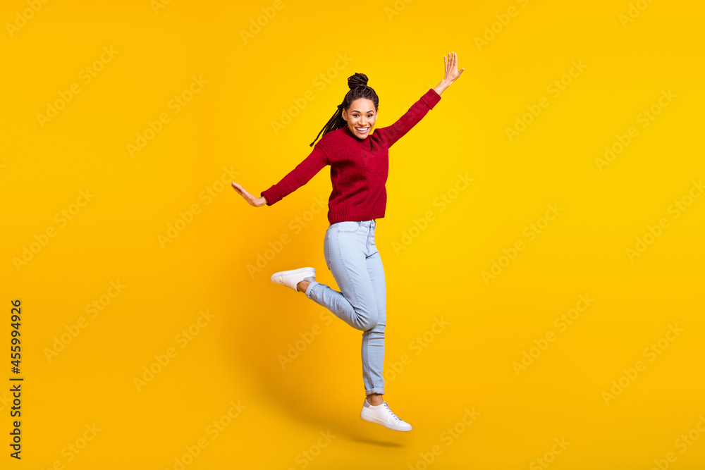 Full length photo of adorable sweet dark skin lady wear red pullover smiling jumping high isolated yellow color background