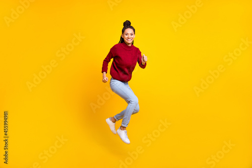 Full length photo of cute adorable dark skin lady wear red pullover smiling jumping high isolated yellow color background