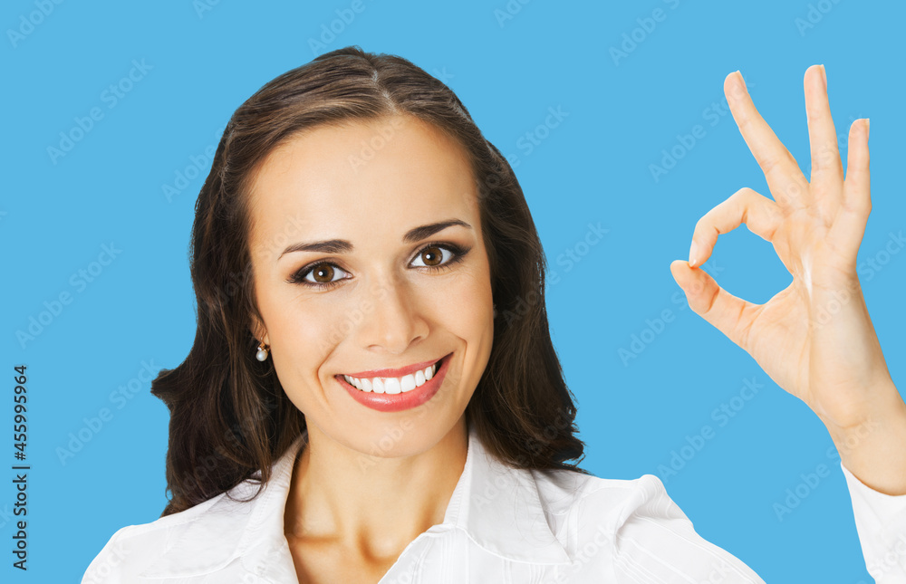 Businesswoman in white confident clothing showing ok hand sign gesture, bright blue color background. Portrait of happy smiling gesturing brunette woman at studio. Business concept photo. Businesswoman in white confident clothing showing ok hand sign gesture, bright blue color background. Portrait of happy smiling gesturing brunette woman at studio. Business concept photo.