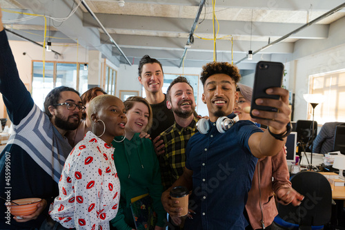 Team talking group selfie with smartphone in office