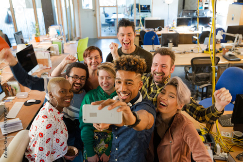 Team talking group selfie with smartphone in office