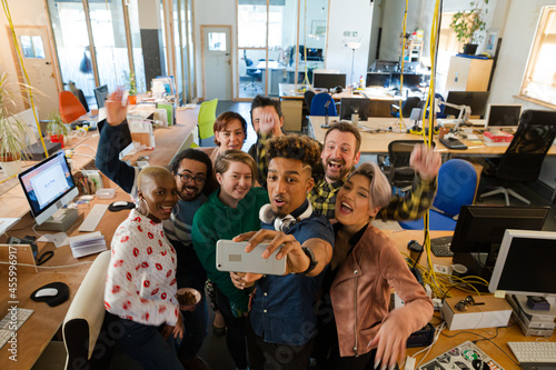 Team talking group selfie with smartphone in office