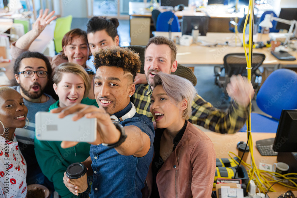 Fototapeta premium Team taking group selfie with smartphone in office