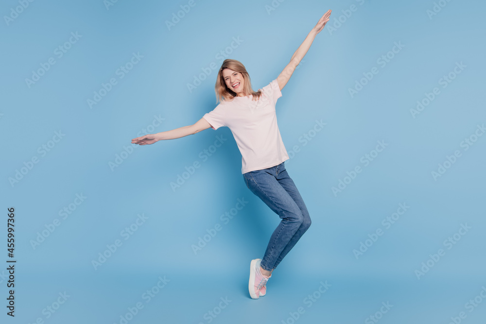 Portrait of positive cheerful lady stand tiptoes raise hands enjoy discotheque on blue background